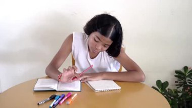 Masada ders çalışan genç bir kız, ödevinden memnuniyet ve ilerleme gösteriyor.