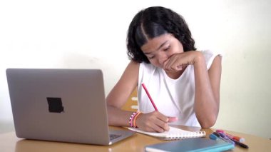 İnternette okuyan Asyalı bir kız düşünceli, düşünceli ve başarılı.