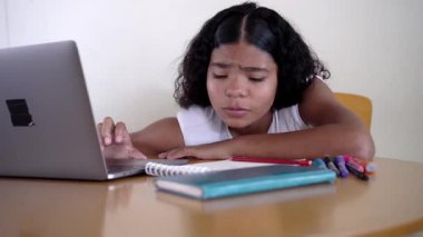 Hispanik kız e-öğrenme seansına konsantre oluyor. Kararlılık ve sessiz ilerleme gösteriyor.