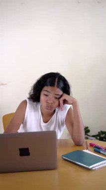 Sıkıcı genç kız öğrenci bilgisayarıyla çalışırken kendini yorgun ve motivasyonsuz hissediyor.