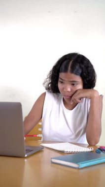 Odaklanmış genç kız, ev ödevini yaparken ilham ve gelişim bulma sıkıntısının üstesinden gelir.