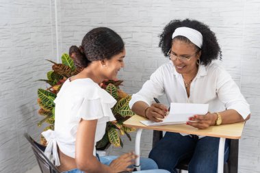 İki neşeli kadın, yüksek öğrenim için evrak işlerini neşeyle tamamlıyor.