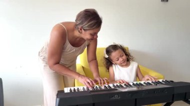 Küçük tatlı kız evde annesiyle birlikte sentezleyici piyano çalmayı öğreniyor.