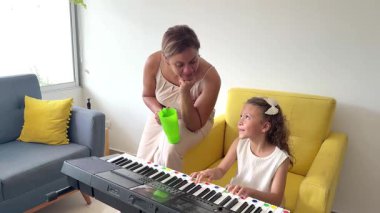 Gururlu müzik öğretmeni, yetenekli öğrencisinin oturma odasında piyano çalışını izliyor.