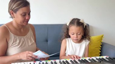 Genç kız müzik öğretmeniyle klavye çalmayı öğreniyor ve beşlikle kutluyor.