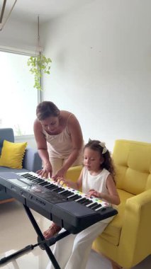 Bayan müzik öğretmeni, küçük bir çocuğa evde elektronik piyano çalmayı öğretiyor.
