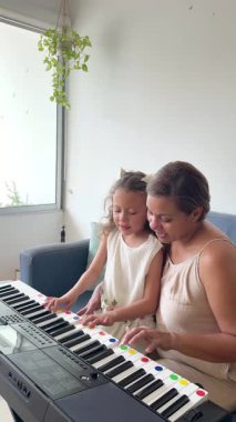 Sevgi dolu anne küçük tatlı kızına evde piyano çalmayı öğretiyor.