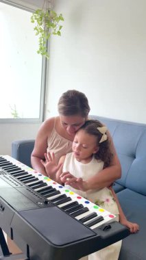 Kıvırcık saçlı genç kız evde müzik öğretmeniyle piyano çalmayı öğreniyor.