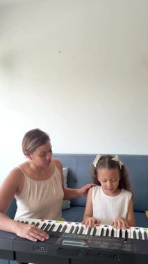 Küçük kızına evde piyano dersi veren özenli bir anne müzikal eğitimi teşvik ediyor.