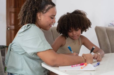 Büyük abla ve küçük kız kardeş birlikte çiziyor, bilgiyi ve yaratıcı eğitimi paylaşıyorlar.