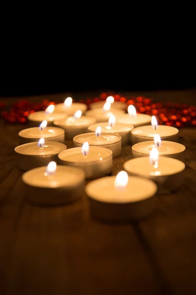 Varias velas ardiendo en la oscuridad sobre una superficie de madera — Foto de Stock