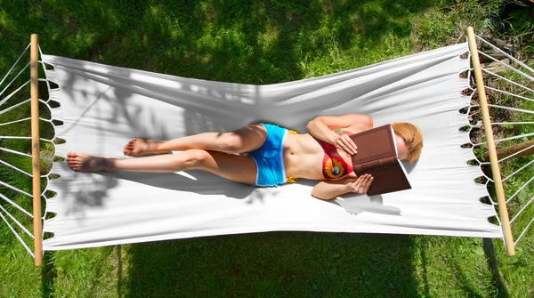 Girl reads a book lying in hammock — Stock Photo, Image