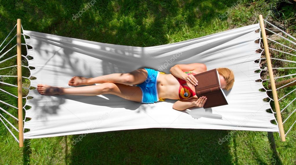 girl reads a book lying in hammock