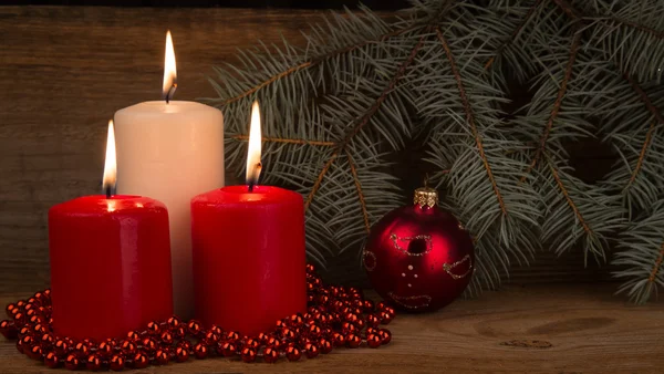 Three burning Christmas candles on the background of fir-tree br — Stock Photo, Image