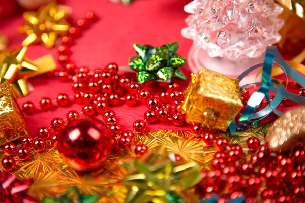 Kleine gouden cadeau-doos in de buurt van rode parel en boog close-up — Stockfoto