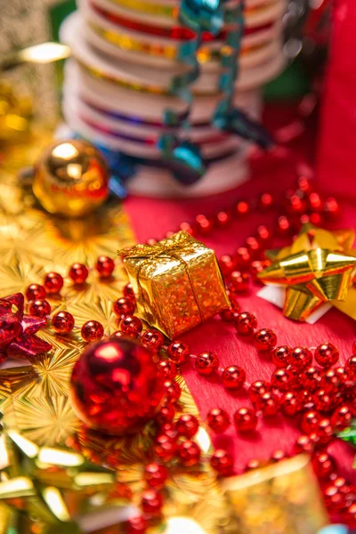 Pequeña caja de regalo de oro cerca de cuentas rojas y el arco de cerca — Foto de Stock