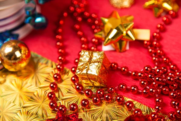 Kleine goldene Geschenkschachtel in der Nähe von roten Perlen und Schleifen in Großaufnahme — Stockfoto