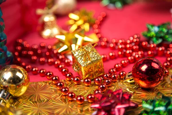 Small golden gift-box near red bead and bow close-up — Stock Photo, Image