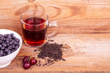 fincan çay, tatlı kiraz ve yaban mersini bir tahta üzerinde beyaz kase