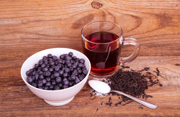 杯茶甜樱桃和蓝莓在木制的白碗 图库照片