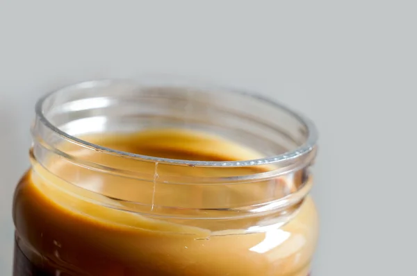 Creamy peanut butter over grey — Stock Photo, Image