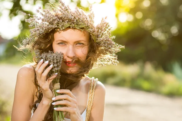 Wanita cantik muda dengan karangan bunga lavender di kepala pada hari musim panas yang cerah — Stok Foto