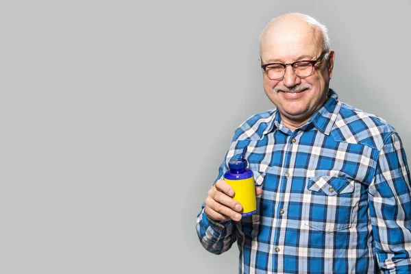 Glücklicher alter Mann hält Flasche mit Vitaminen glücklich lächelnd — Stockfoto