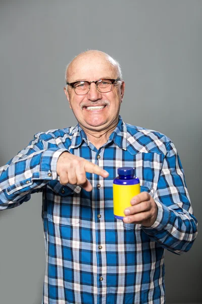Счастливый старик держит бутылку с витаминами — стоковое фото
