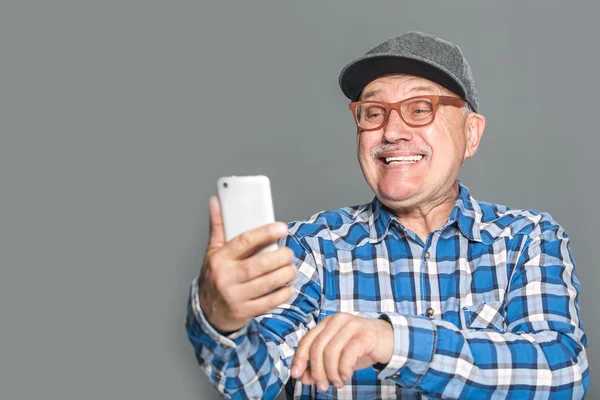 Viejo hombre activo usando teléfono móvil aislado sobre fondo gris — Foto de Stock