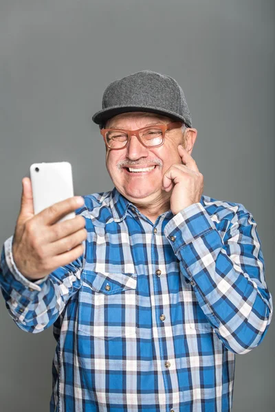 Viejo hombre activo usando teléfono móvil aislado sobre fondo gris — Foto de Stock