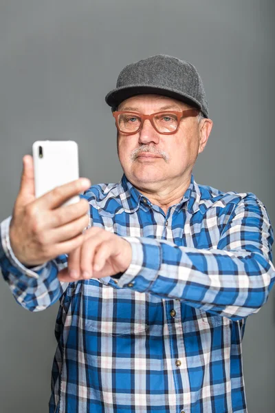 Viejo hombre activo usando teléfono móvil aislado sobre fondo gris — Foto de Stock