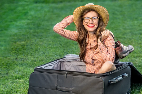 Beautiful traveler with suitcase over green grass background — Stock Photo, Image