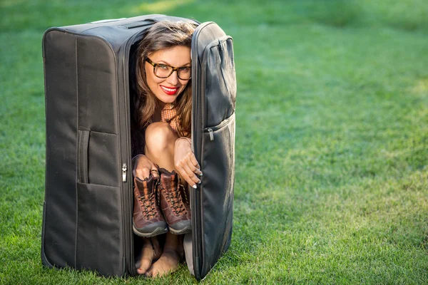 Beautiful traveler with suitcase over green grass background — Stock Photo, Image