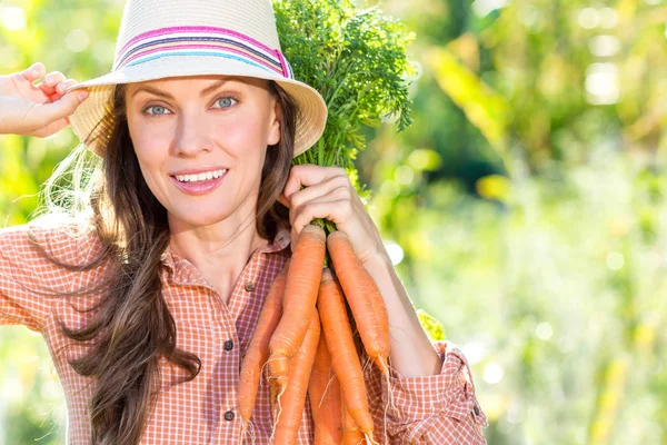 Mulher com cenouras orgânicas em uma horta — Fotografia de Stock