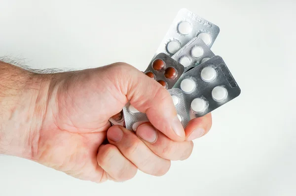 Рука тримає таблетки ізольовані над білим — стокове фото