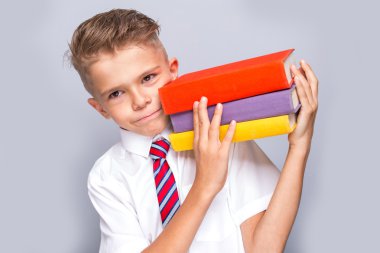 Gri bir arka plan üzerinde neşeli gülümseyen küçük çocuk