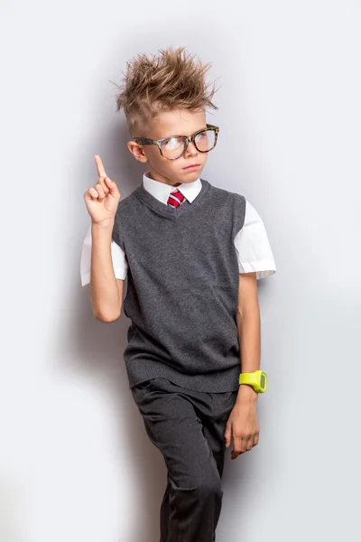 Netter Schuljunge, der mit erhobenem Finger über grauem Hintergrund steht. zurück zum Schulkonzept — Stockfoto