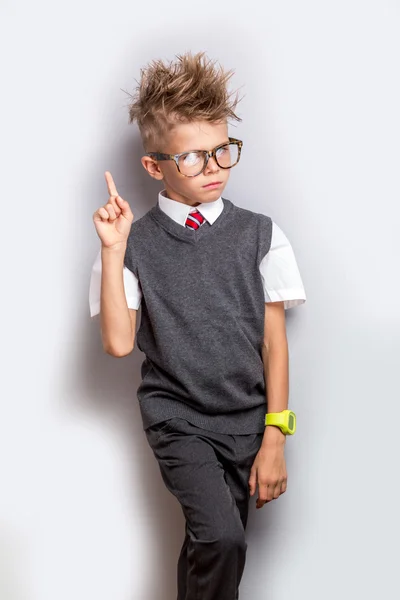 Mignon écolier debout sur fond gris avec doigt vers le haut. Concept de retour à l'école — Photo