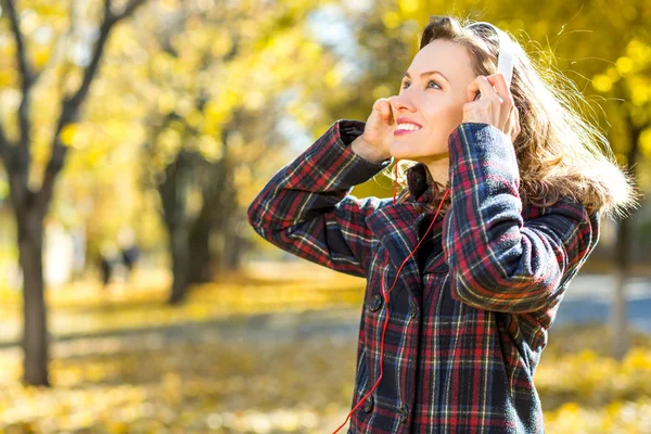 Beautiful girl listening to music in autumn yellow park — Stock Photo, Image