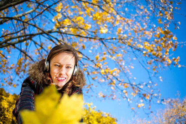 Hermosa chica escuchando música en el parque amarillo de otoño — Foto de Stock