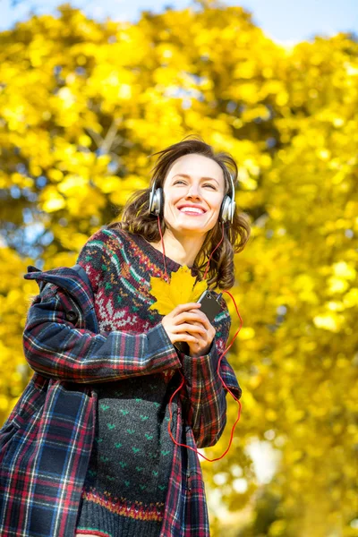 Beautiful girl listening to music in autumn yellow park — Stock Photo, Image
