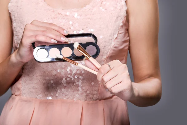Женщина держит щетки для макияжа и тени — стоковое фото