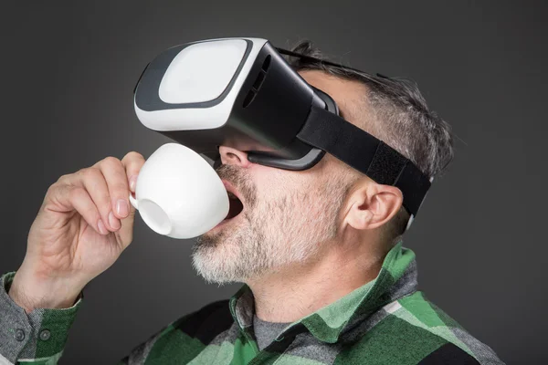 Забавна людина у окулярах віртуальної реальності на сірому фоні — стокове фото