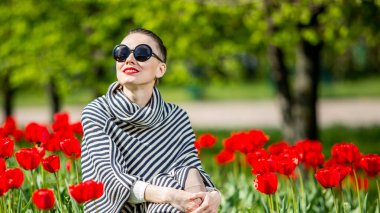 Beautiful woman in spring park among tulip field