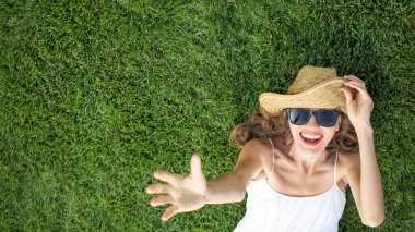 Şapka ve güneş gözlüğü takan ve yeşil çimlerin üzerinde uzanan kadın. 