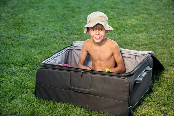 Adorable small boy in huge suitcase. Planning travel during quarantine concept