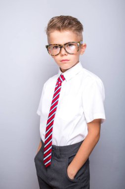 Beyaz gömlek, kravat ve gri arka planda gözlük takan yakışıklı zarif çocuk.