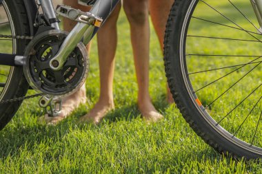 Baba ve oğul güneşli bir yaz gününde bisiklete bakıyorlar.