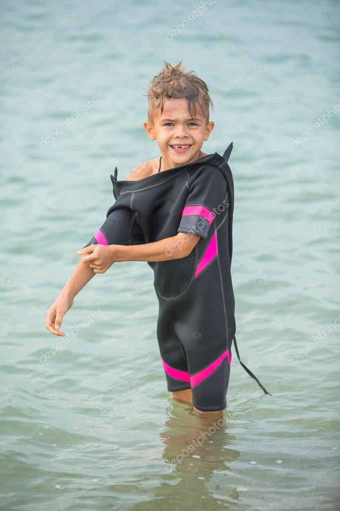 Cute little boy in wetsuit after diving in sea Stock Photo by