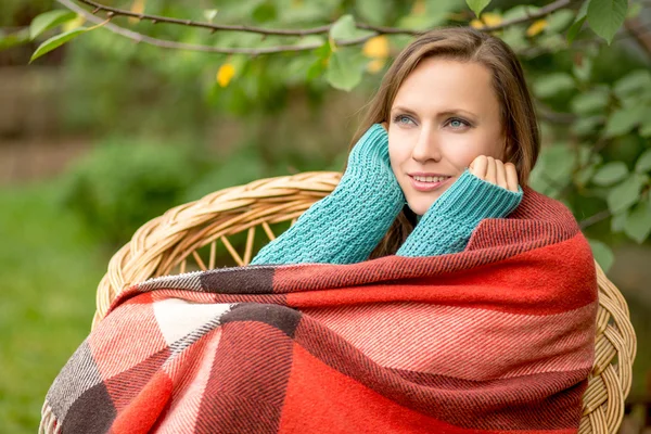 Beautiful woman in the garden wrapped in a plaid blanket — Stock Photo, Image